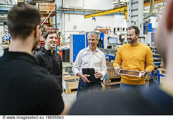 Happy businessmen conducting meeting with team at factory