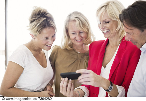 Happy businesspeople using cell phone at office