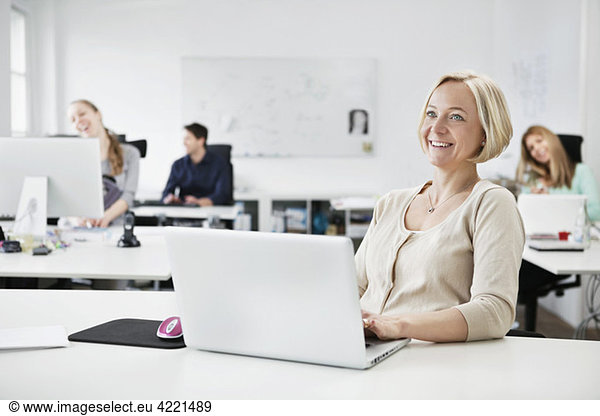Happy businesswoman by desk