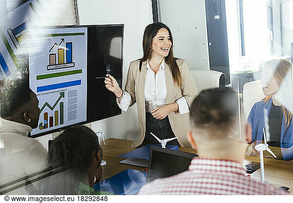Happy businesswoman discussing renewable energies over graphs in meeting at office