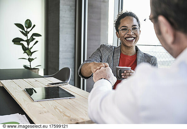 Happy businesswoman doing fist bump with colleague in office