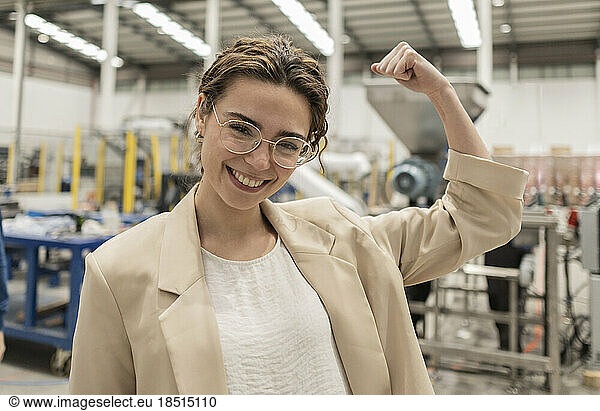 Happy businesswoman flexing muscles in industry