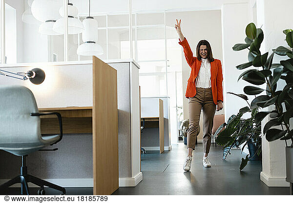 Happy businesswoman gesturing peace in office