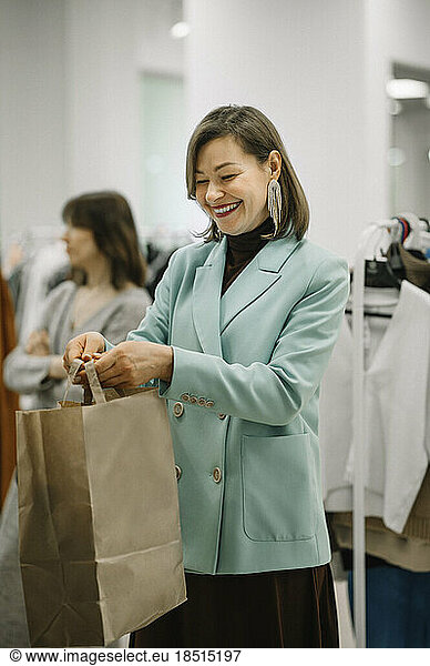 Happy businesswoman giving shopping bags in store