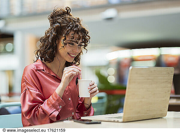 Happy businesswoman having coffee and freelancing on laptop in cafe