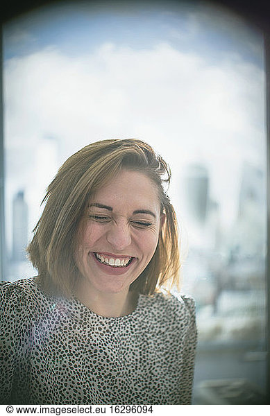 Happy businesswoman laughing in window