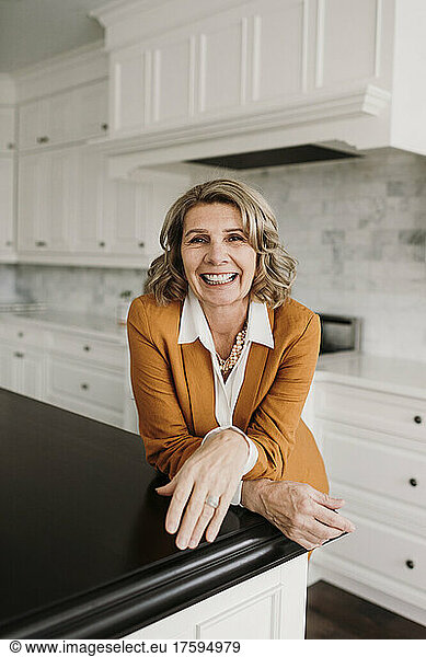 Happy businesswoman leaning on kitchen counter at home