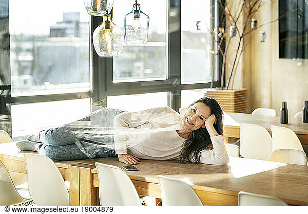 Happy businesswoman lying on table seen through glass