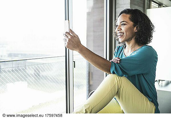 Happy businesswoman on video call through mobile phone in office