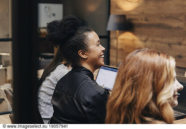 Happy businesswoman sitting amidst female colleagues in board room during meeting