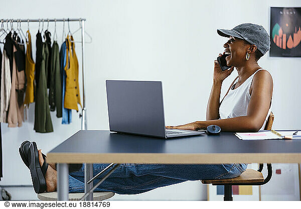 Happy businesswoman talking on mobile phone sitting at desk in office
