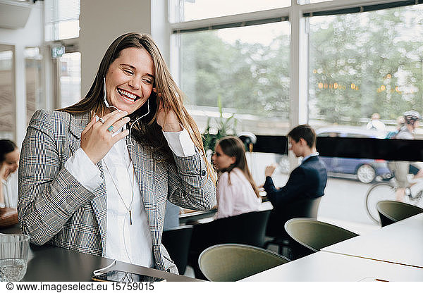 Happy businesswoman talking through headphones at creative coworking space