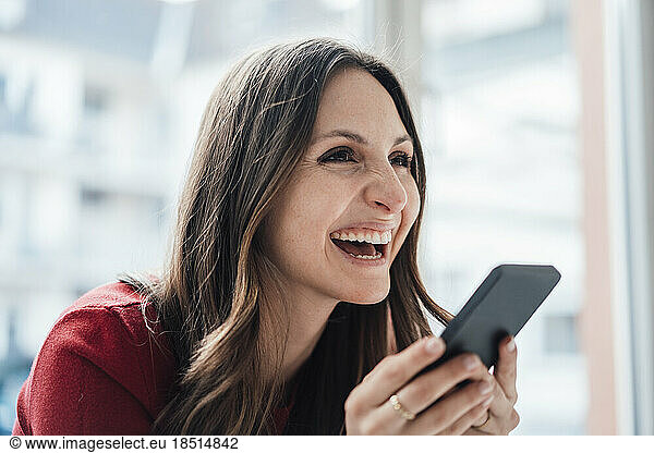 Happy businesswoman talking through speaker phone