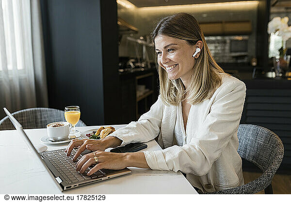 Happy businesswoman using laptop at restaurant