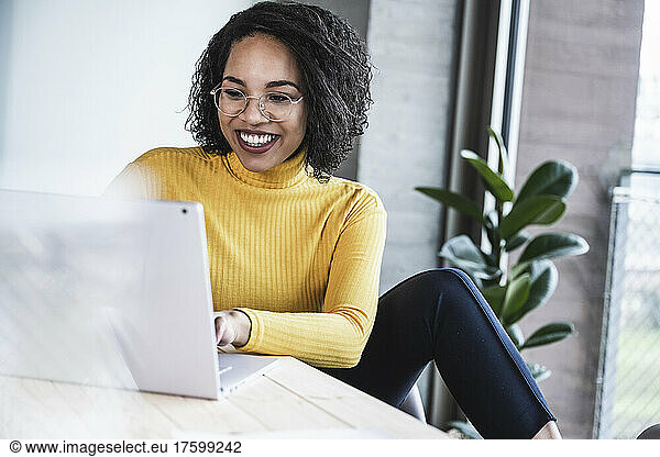 Happy businesswoman using laptop at work place