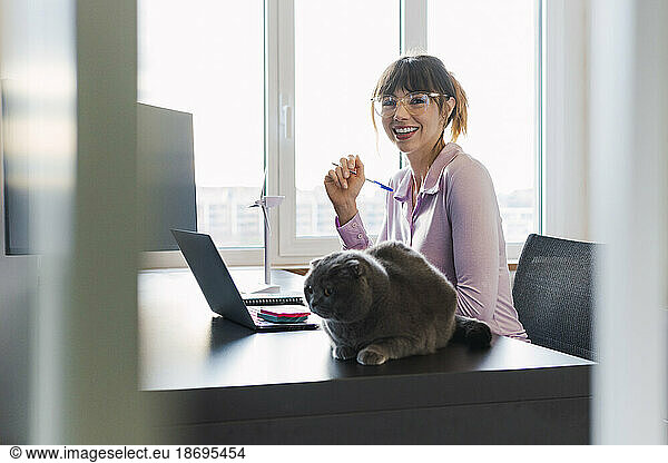 Happy businesswoman wearing eyeglasses sitting at desk
