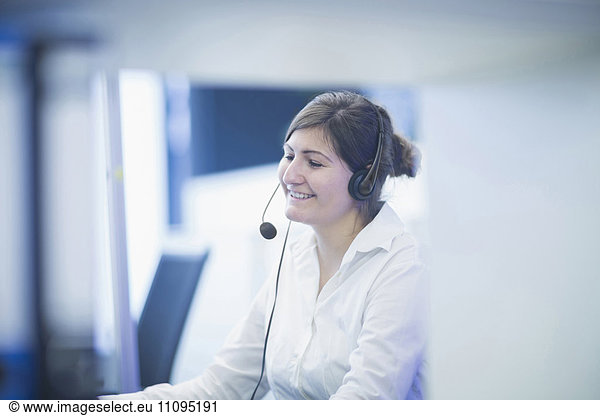 Happy businesswoman wearing headset and working in office  Freiburg Im Breisgau  Baden-Württemberg  Germany