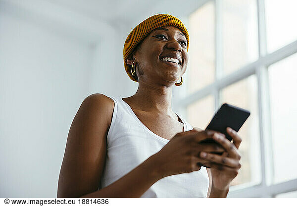 Happy businesswoman wearing knit hat holding smart phone