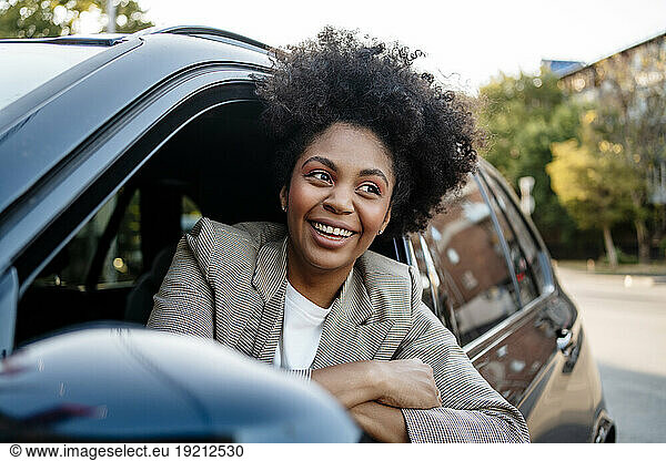 Happy businesswoman with arms crossed sitting in car