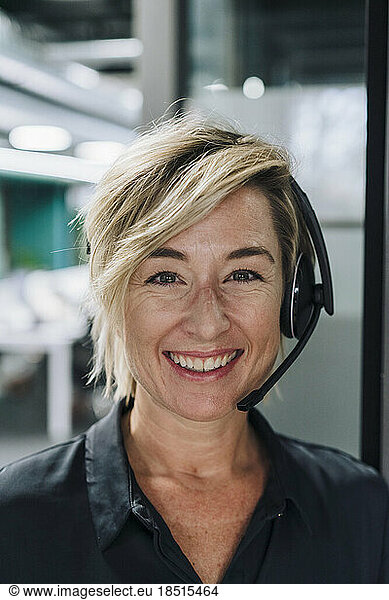 Happy businesswoman with blond hair wearing headset in office