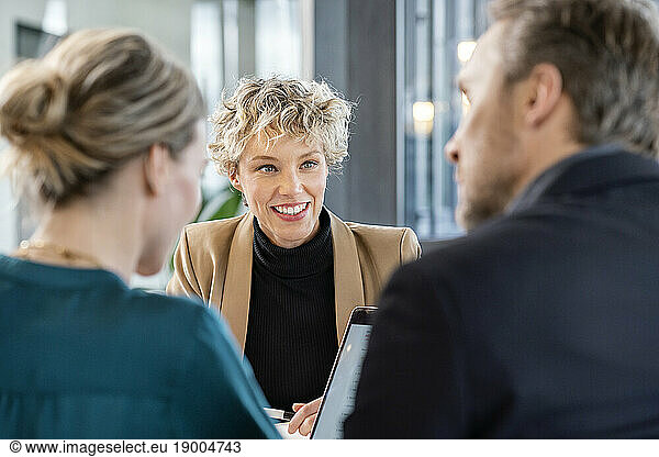Happy businesswoman with colleagues sitting in office