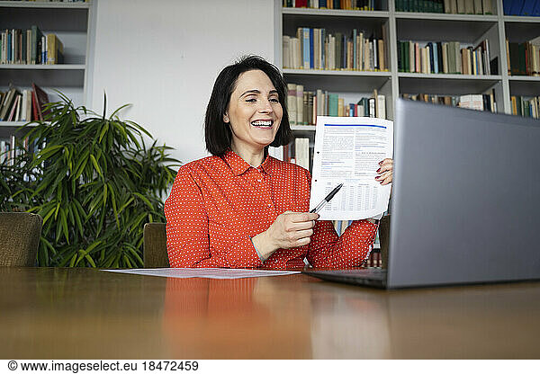 Happy businesswoman with document talking on video call