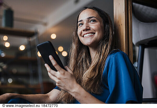 Happy businesswoman with smart phone at office
