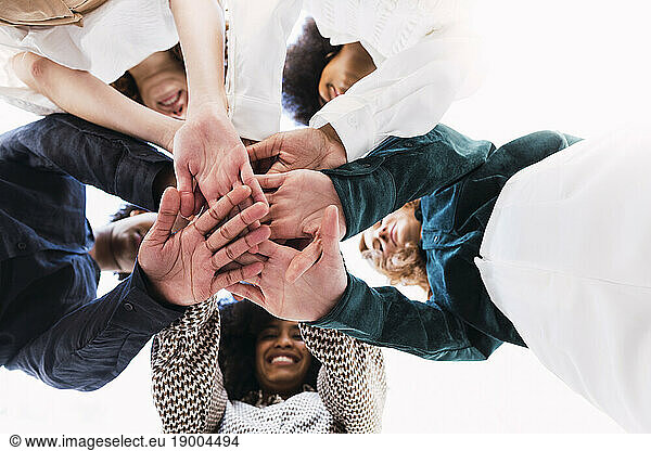 Happy businesswomen stacking hands and huddling together in unity