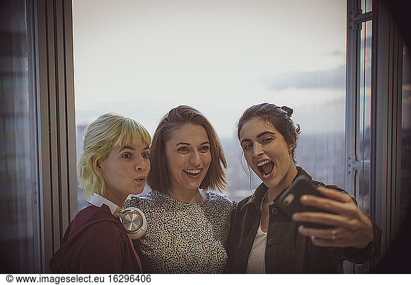 Happy businesswomen taking selfie at office window