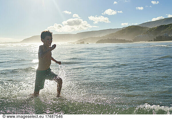Happy carefree boy running in sunny ocean surf