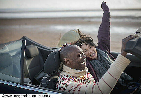 Happy carefree couple in convertible on winter beach