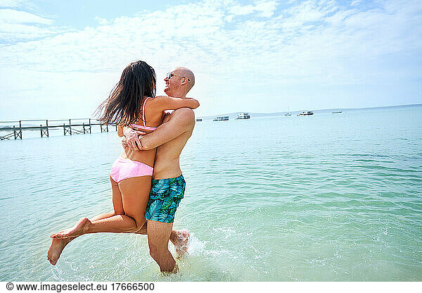 Happy  carefree couple playing in sunny summer ocean
