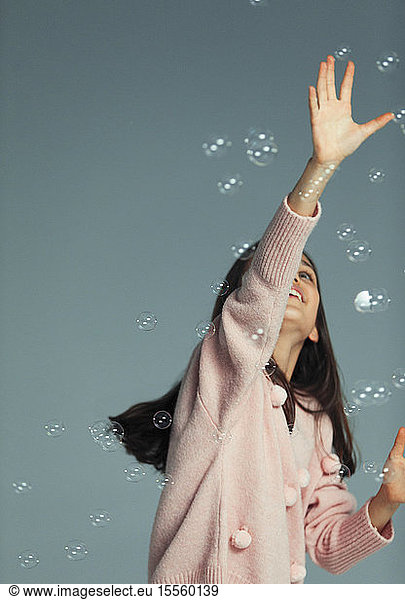Happy  carefree girl playing  reaching for bubbles