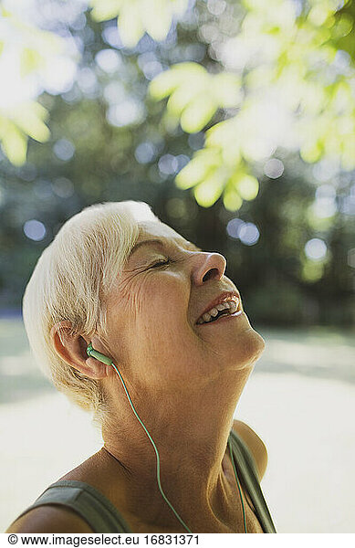 Happy carefree senior woman listening to music with headphones
