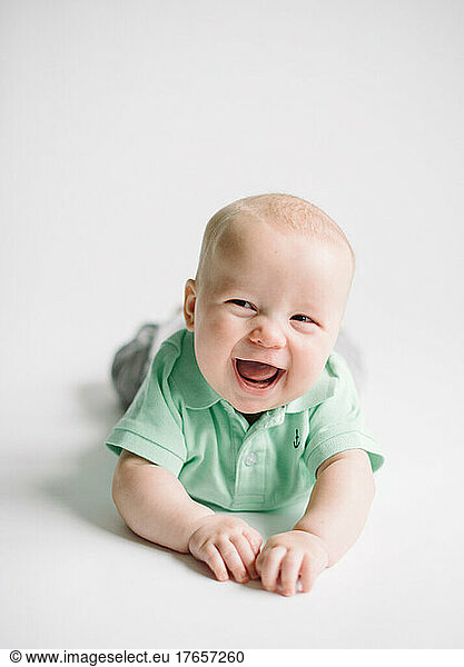 Happy Caucasian baby boy on white background wearing a green shirt