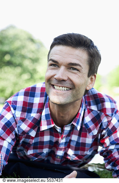 Happy cheerful mature man lying on front in grass
