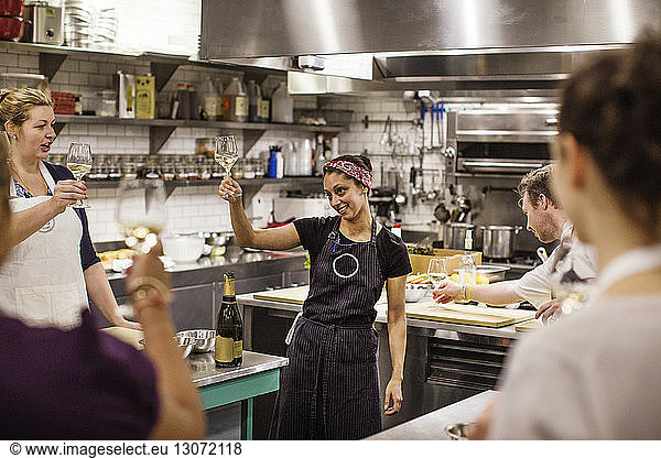 Happy chef raising a toast while standing at commercial kitchen