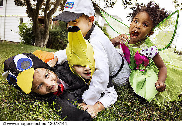 Happy children in Halloween costumes playing on grass