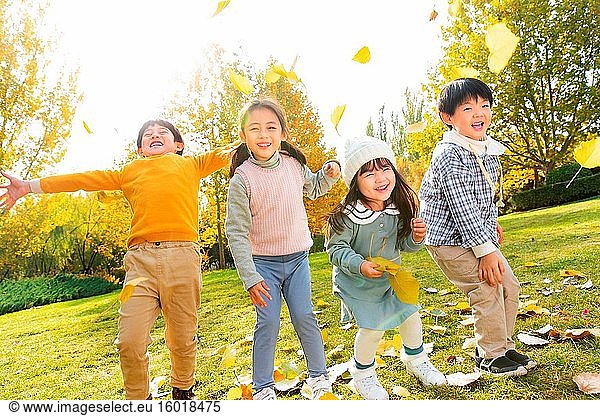 Happy children playing in the park the leaves