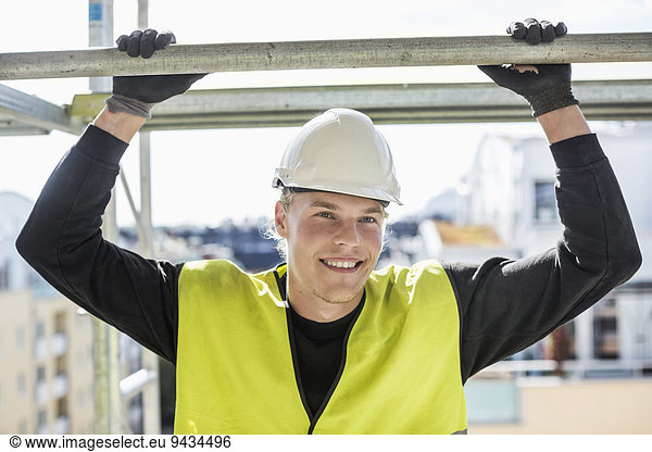 Happy construction worker looking away while standing at site