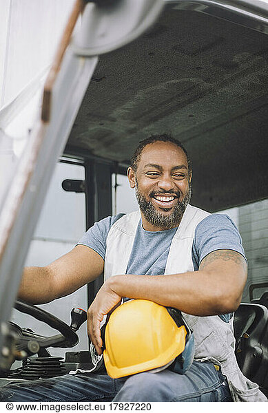 Happy construction worker with hardhat sitting in vehicle
