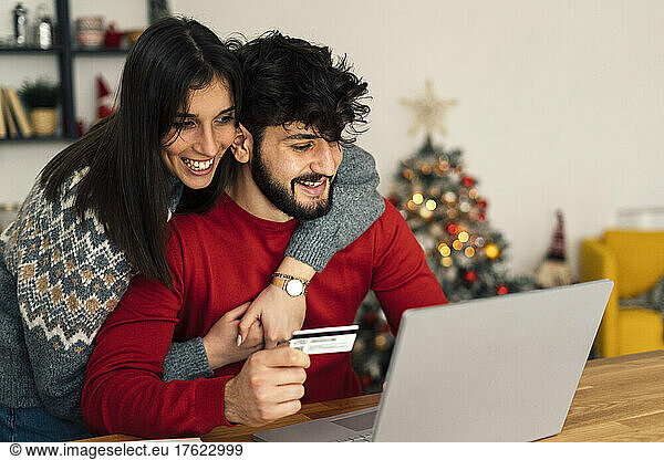Happy couple doing online shopping using laptop at home