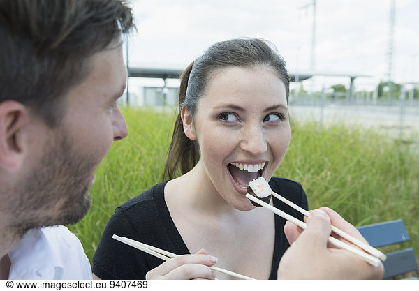 Happy couple eating sushi outdoors