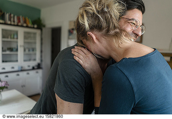Happy couple embracing in kitchen at home
