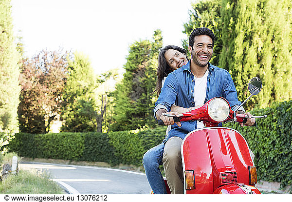 Happy couple enjoying motor scooter ride at park