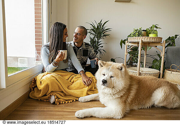 Happy couple having coffee with dog sitting in foreground