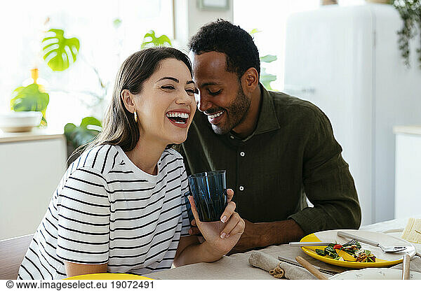Happy couple having lunch at dining table in kitchen