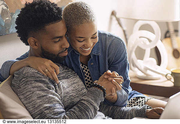 Happy couple holding hands while sitting on bed at home