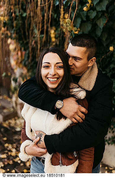Happy couple hugging fooling around in autumn park