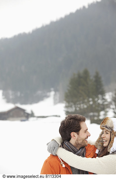 Happy couple hugging in snowy field